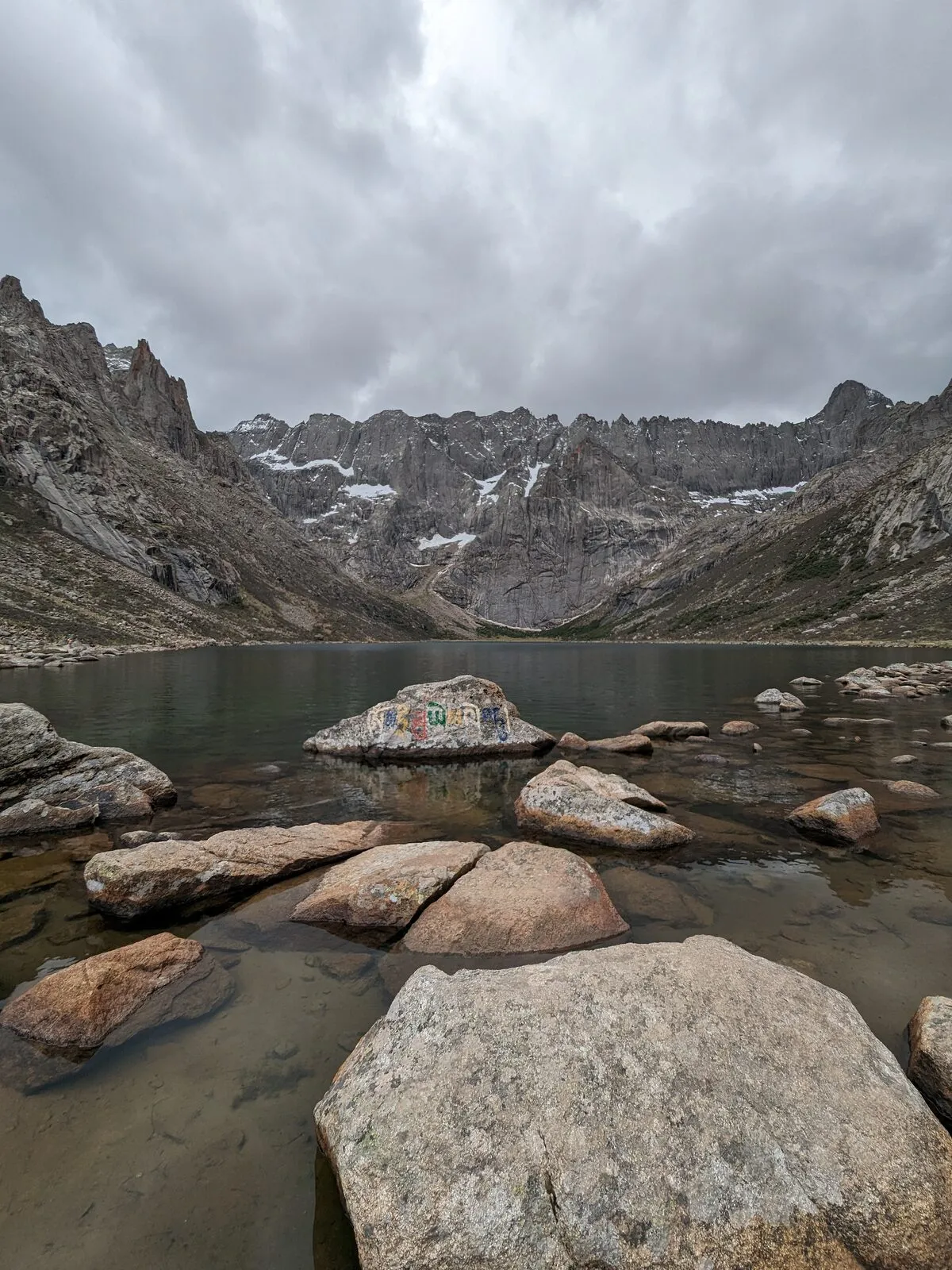 Lac d'altitude sur le plateau tibétain du Sichuan, pierre mani gravée d'un mantra sur la rive